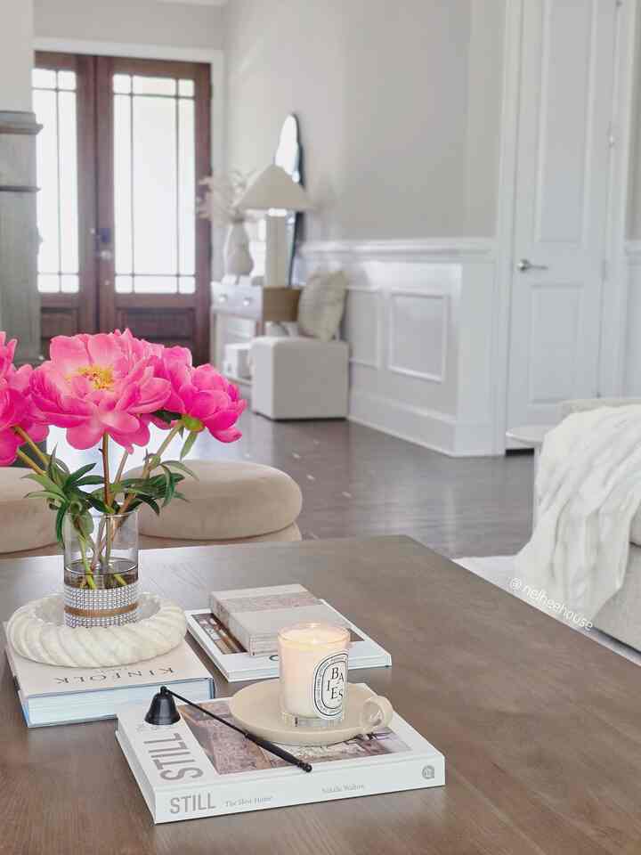 Natural color living room featuring a light brown coffee table with pink flowers and a lit candle on top, creating a simple atmosphere