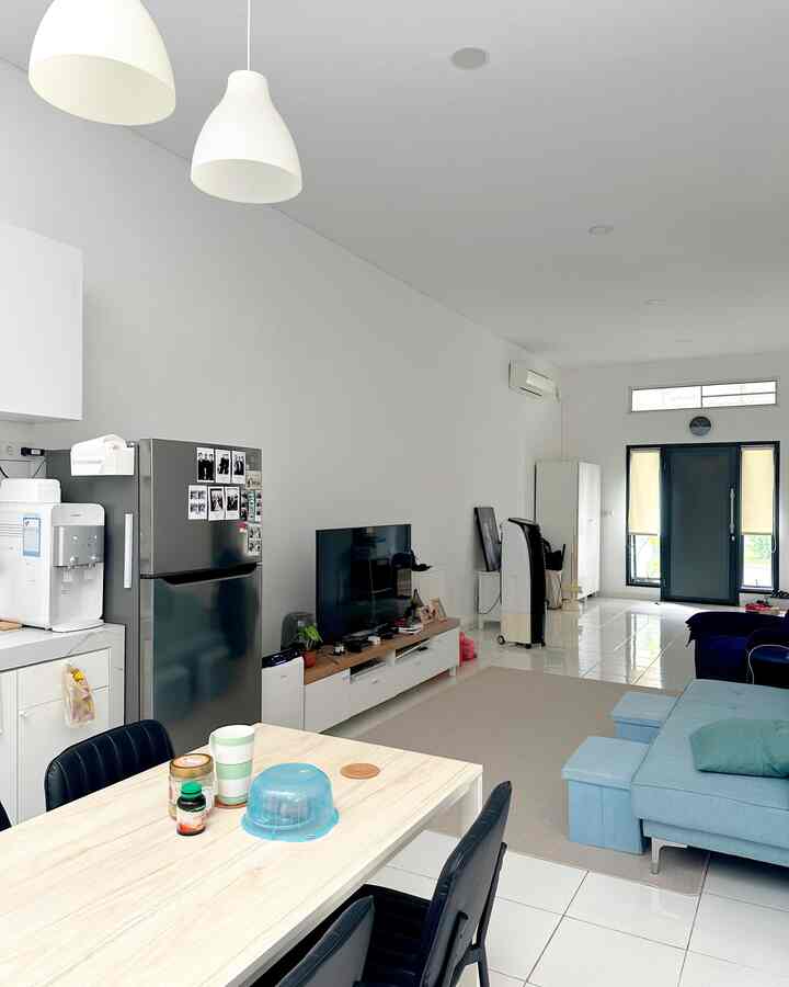 White and blue toned living and kitchen area featuring a sofa bed and dining table in a clean, minimal interior