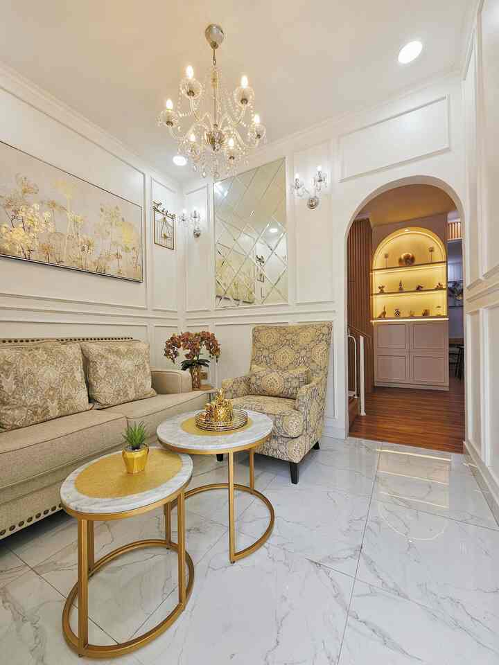 White and gold toned living room featuring sofa, armchair, marble coffee tables creating a luxurious and modern atmosphere