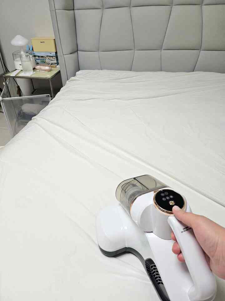 白色調の寝室、グレーのファブリックベッドフレームと白い寝具が配置された清潔感のあるインテリア