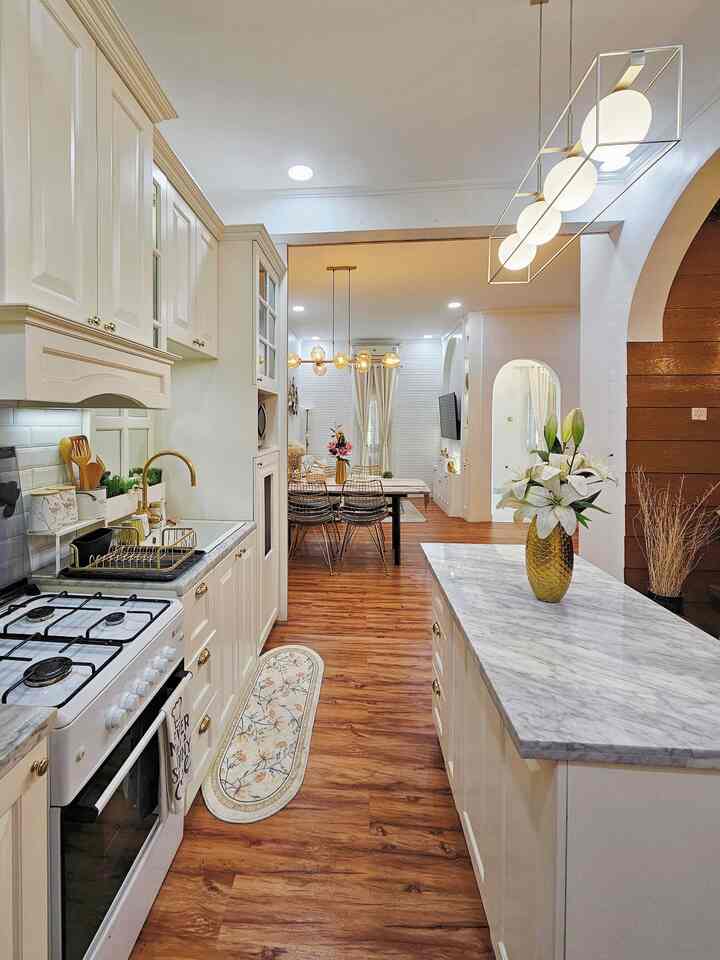 White and wood tone kitchen and dining room featuring central island and gold accents in a natural modern interior