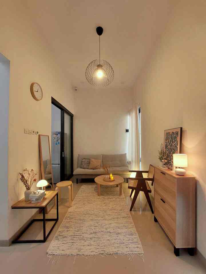 Natural tone living room with white walls and beige furniture, featuring a simple sofa, round coffee table, and warm lighting creating a cozy atmosphere