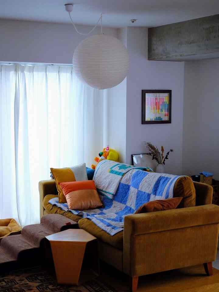 Natural color and white toned living room featuring a brown sofa, pendant light, pet steps, and stools creating a cozy atmosphere