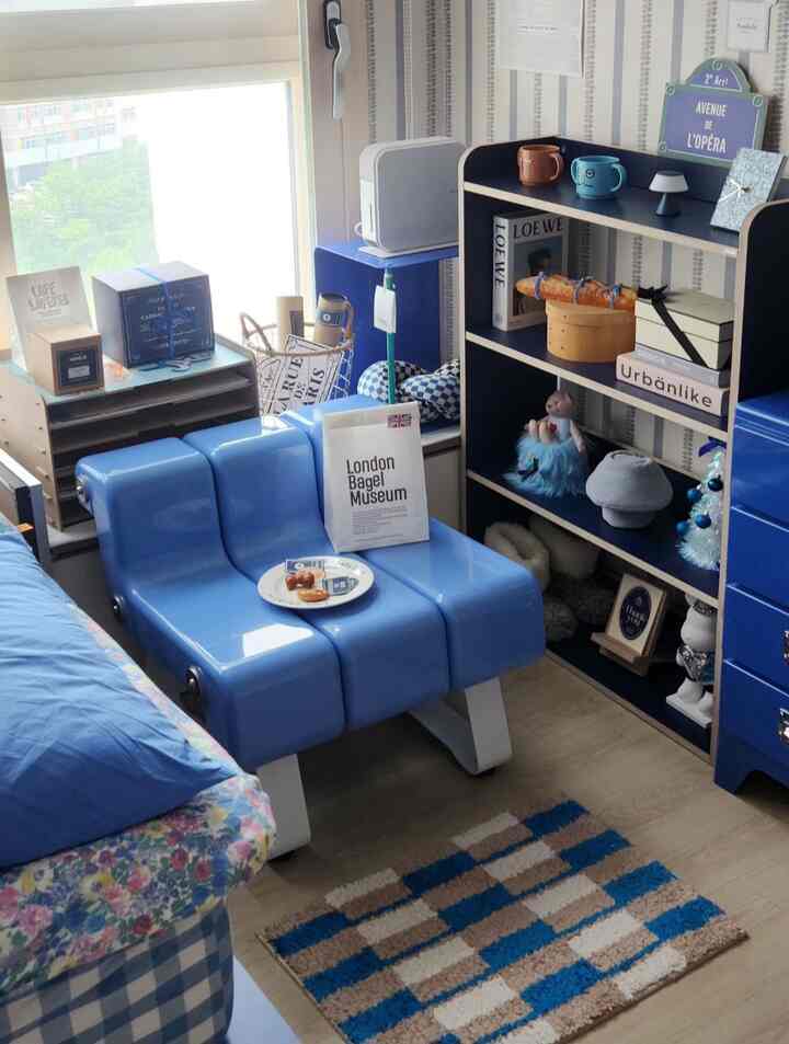 明るいブルーの色調の寝室、ブルースツールと本棚が配置された雰囲気のあるヴィンテージ空間