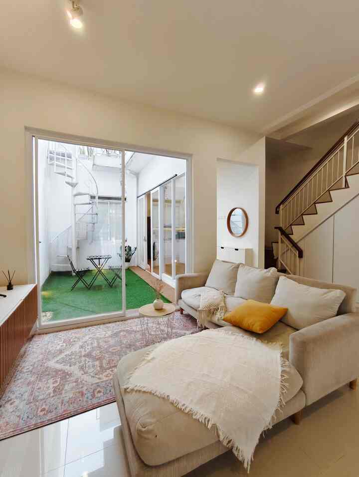Beige sofa and natural wooden table in a natural-toned living room, featuring a small artificial grass balcony visible through glass doors