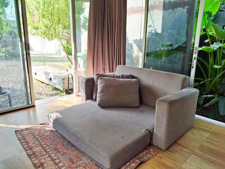 Natural tone living room with blackout curtains, modern sofa bed and rug creating a cozy atmosphere