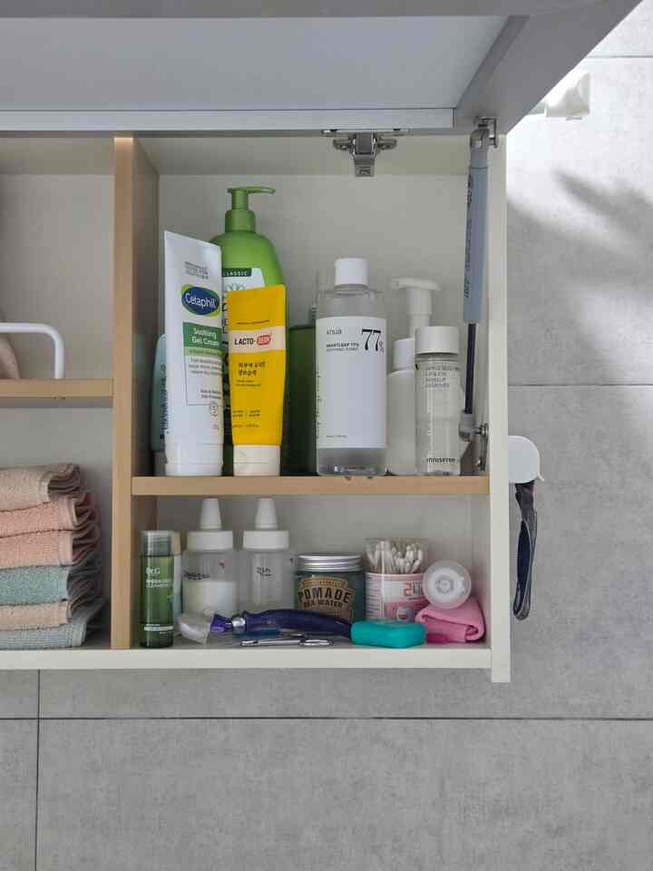 ナチュラルカラーのトイレ収納棚にスキンケア用品とタオルが整頓された清潔感のあるスペース