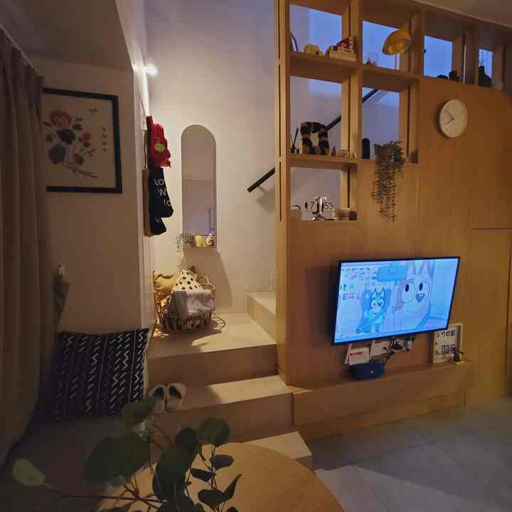 Cozy compact living room with warm wood tones and soft lighting, featuring a wall mirror and a TV