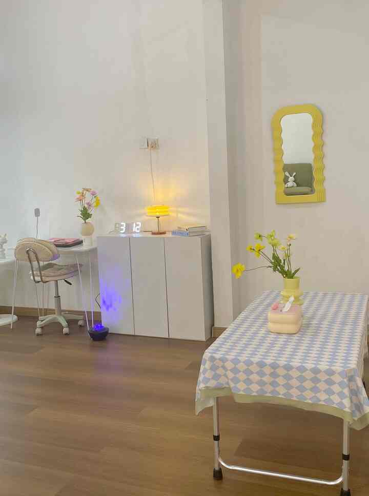 White and brown toned living room featuring white storage cabinet, yellow table lamp, and checkered tablecloth creating a cozy atmosphere