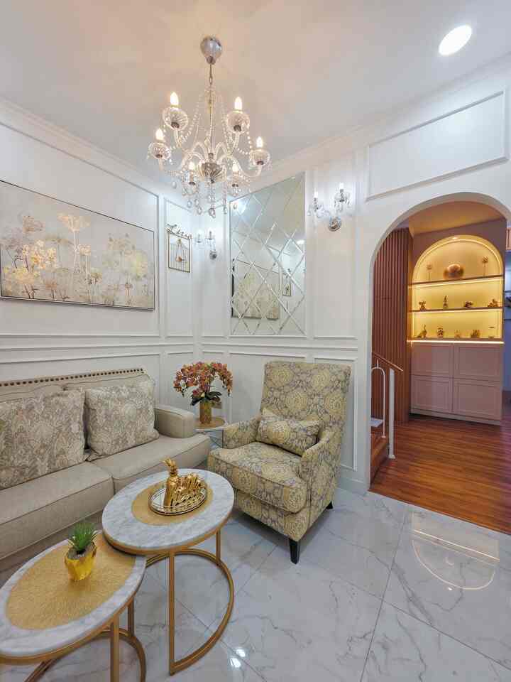 Classic living room in white and gold tones featuring a chandelier, wall art, elegant sofa and armchair