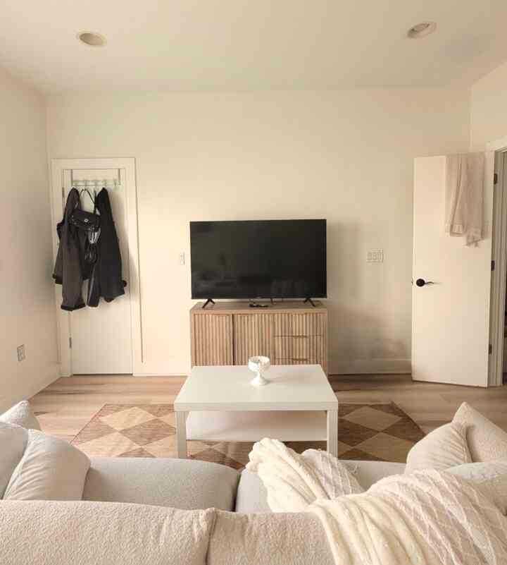 Warm natural color tone living room featuring wooden TV stand and white coffee table with a simple modern atmosphere