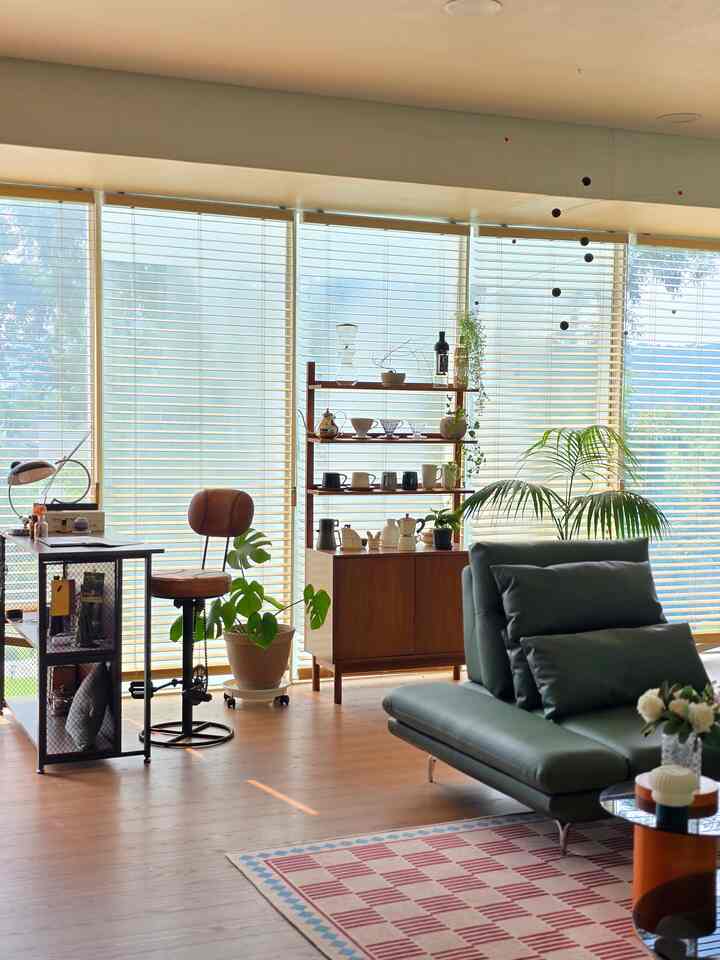 Bright living room with natural wood tones and subdued green sofa featuring a cozy home cafe setup