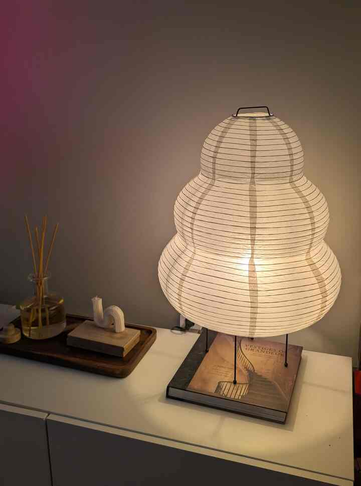 Warm-toned Japandi-style space featuring a round white lamp centrally placed on a shelf alongside diffuser and candle creating a cozy atmosphere