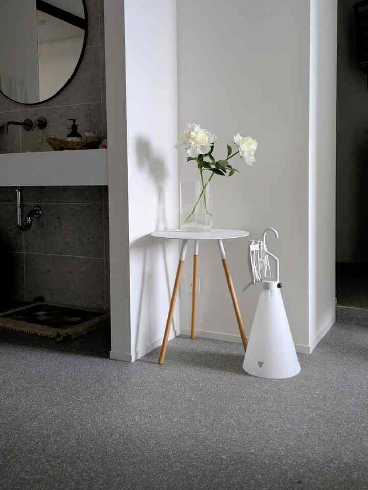 White and wood-toned entrance featuring a small round table with a vase of flowers, creating a minimal and natural atmosphere