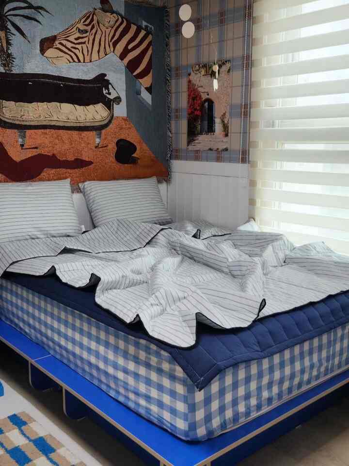 ブルーとホワイトの色調が印象的な寝室、チェック柄のマットレスとストライプの掛け布団カバーが配置された落ち着いた空間