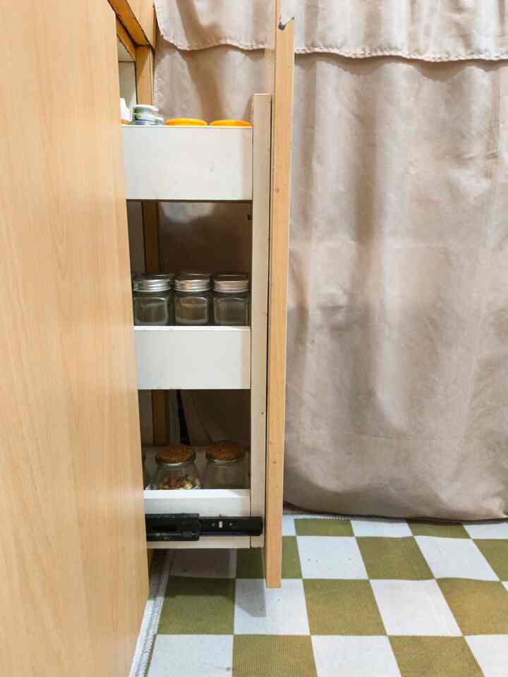 Kitchen space featuring a beige curtain and green-white checkered carpet with a visible gap storage cabinet