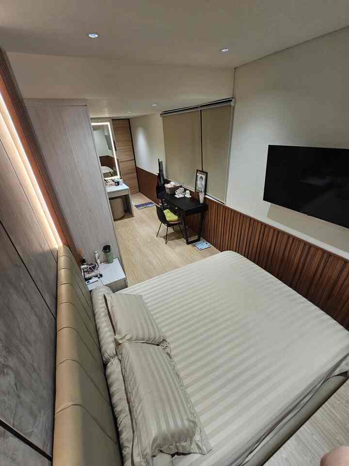 Untuk kamarku yang bentuknya memanjang, letak divan sengaja kutempatkan di ujung ruangan agar space di tengah menjadi lebih lapang. Lemari pakaian dibuat custom built-in pada saat renovasi dengan warna HPL yang sesuai dengan warna nakas di samping kiri dan kanan divan. 
Aku hanya menambahkan satu meja kerja di kamar ini, agar kamar tidak terlalu sesak. 
Seperti halnya di ruang tamu dan ruang makan, di kamarku aku juga menggunakan WPC sebagai aksen di sepanjang dinding. 
Untuk lantai juga hanya di kamar ini yang menggunakan SPC, karena aku ingin suasana kamar menjadi lebih hangat.

#LantaiSPC
#WallPanelEstetik
#RollerBlind
#DivanMinimalis
#KursiEstetik
#StoolMinimalis
#BedRoomStyling
#InspirasiKamar
#KamarTidurNyaman
