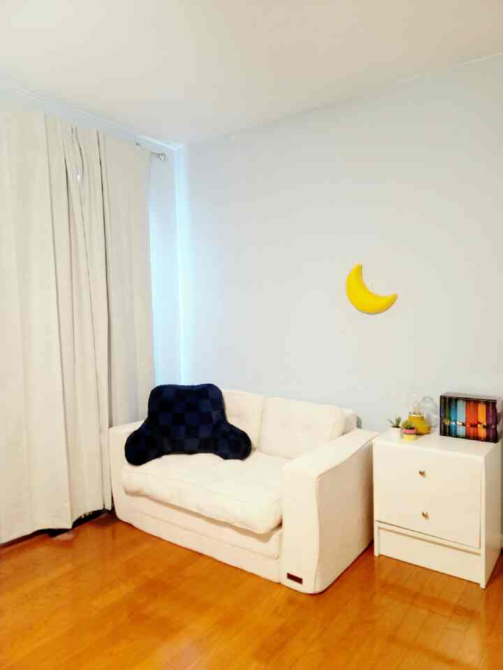 White and brown toned kids' reading nook featuring a sofa and nightstand in a simple, cozy space