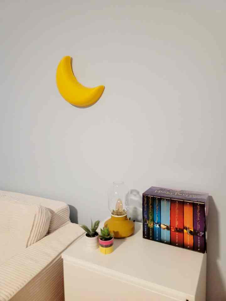 White and yellow toned kids' reading nook featuring sofa, dresser, and lighting creating a simple and cozy corner