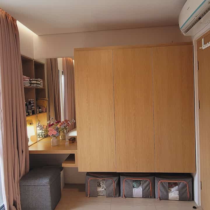 Beige walls and floor with natural oak closet and vanity, pink curtains creating a neat storage space
