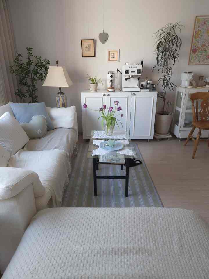 白と青のトーンのリビング、ソファとコーヒーテーブル、フロアランプと観葉植物が調和した居心地の良い空間