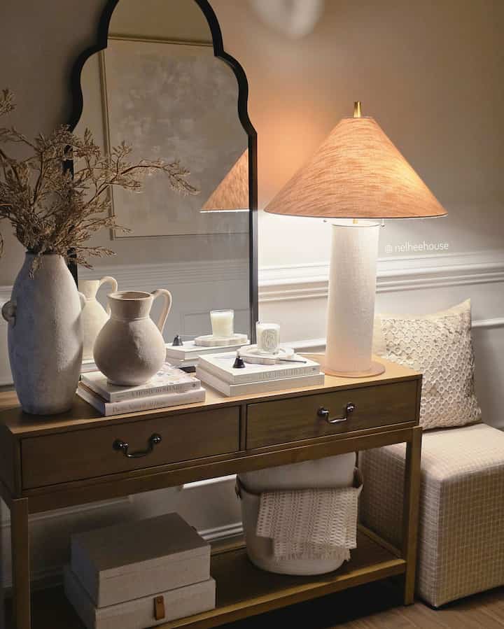 Warm brown and ivory toned entrance featuring a console table, ottoman, and table lamp creating a cozy atmosphere