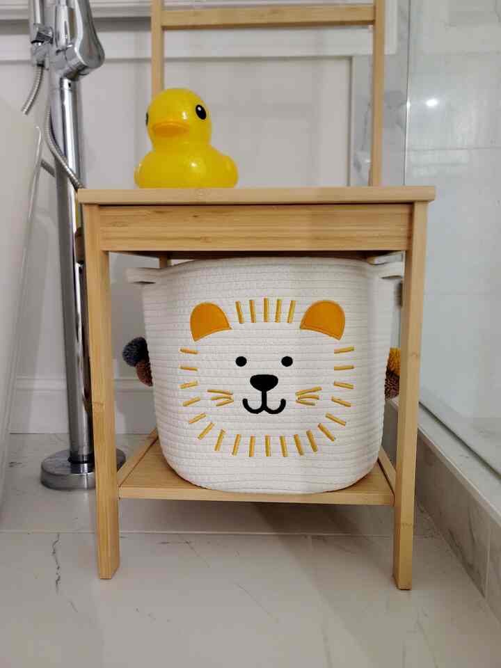 Bright wood-tone shelf unit with an adorable lion-design storage basket in a bathroom setting