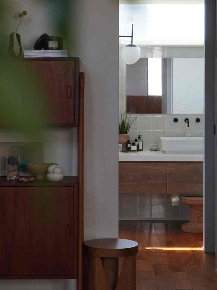Natural tone entrance and bathroom featuring beige walls and wood-tone furniture with a calm atmosphere
