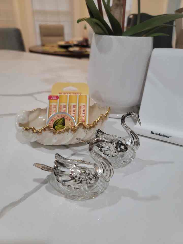 A stylish decor space featuring artistic white and gold swan figurines and a gold-edged white dish on a table.