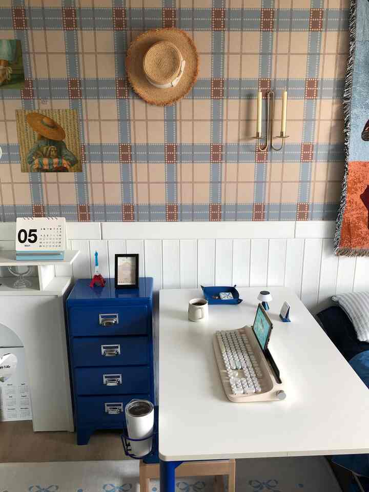 ホワイトとブルーのトーンのホームオフィス、シンプルなデスクとブルーの収納が配置された落ち着いたインテリア