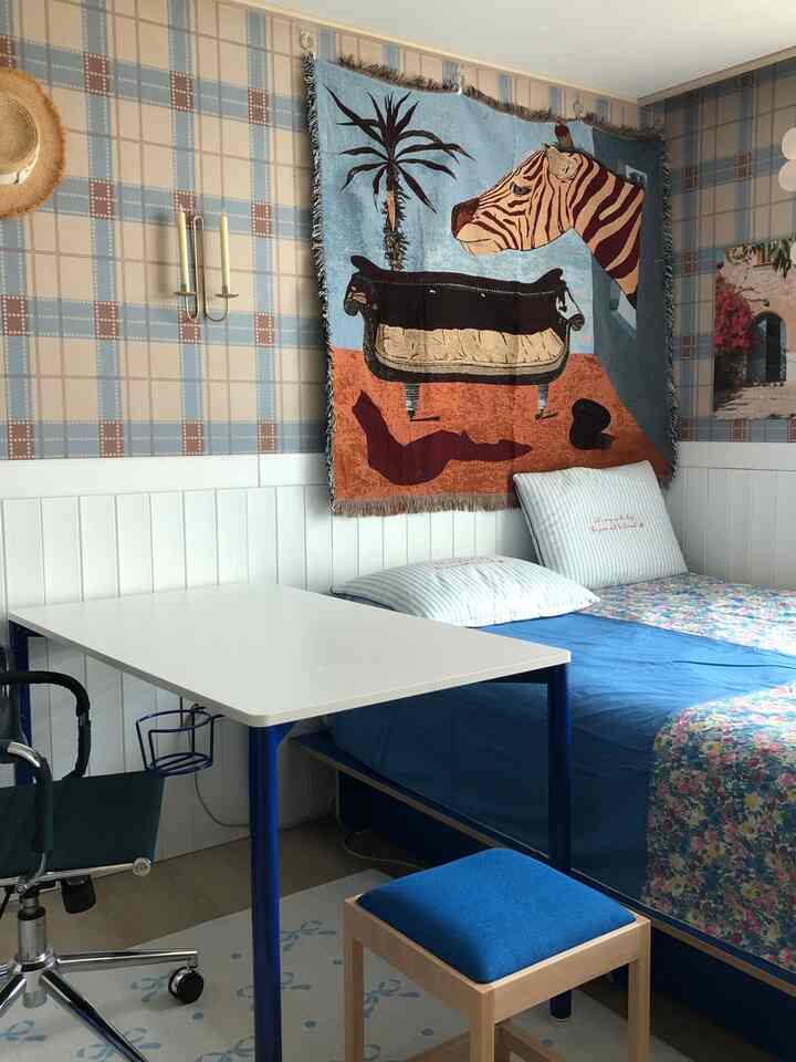 Blue and white toned bedroom featuring a mid-century modern desk and stool in a cozy space