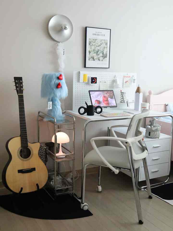 White and metal toned home office featuring a desk, office chair, and guitar creating a clean workspace