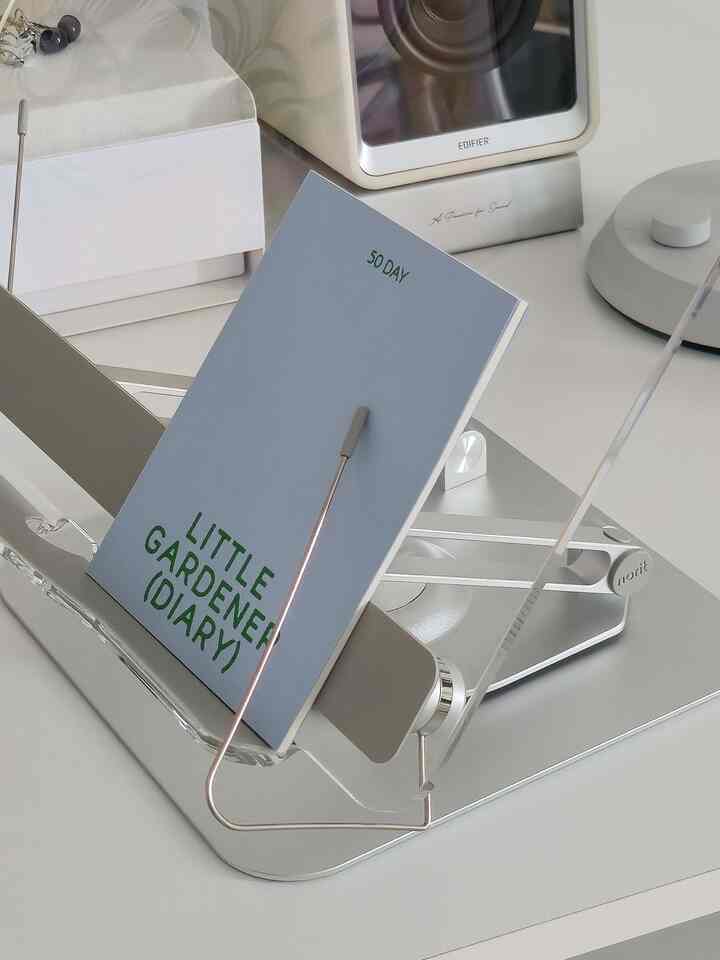 Clean workspace featuring transparent acrylic and silver metal desk monitor stand and storage rack