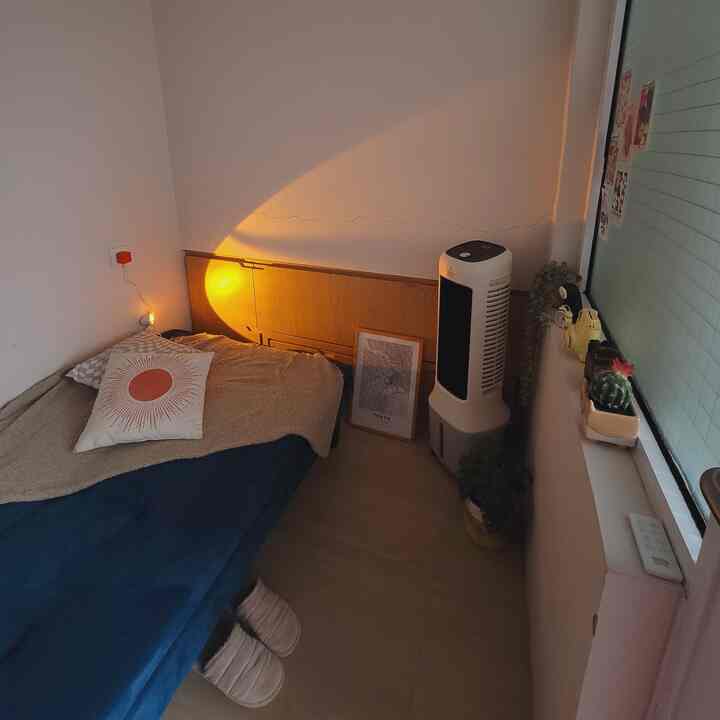 Natural-toned small 6-tatami bedroom with warm orange stand lamp lighting, bed with cushions and blanket arranged