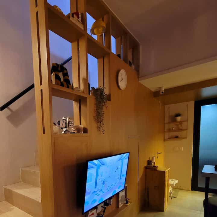 Wood tone and white color blend in a well-laid-out living room featuring a TV and storage unit with cozy interior