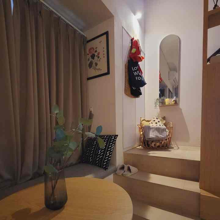 Natural-toned small entrance space featuring a wooden table, arched mirror, and storage basket with a cozy atmosphere