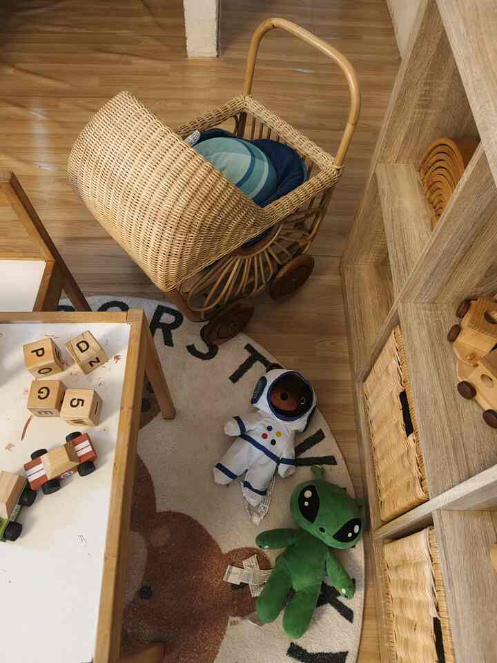 Natural wood-toned kids' room featuring toy storage baskets and a carpet with playful toys arranged for a cozy atmosphere