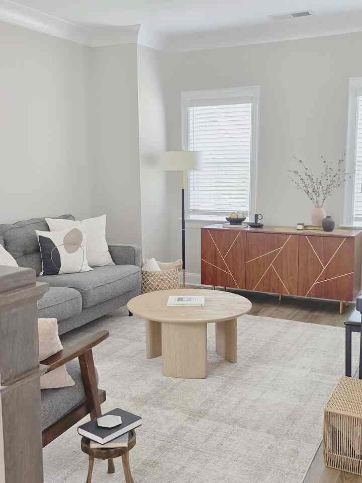 A bright living room with white walls, gray sofa, and natural wood tones, featuring a cozy and simple modern atmosphere.
