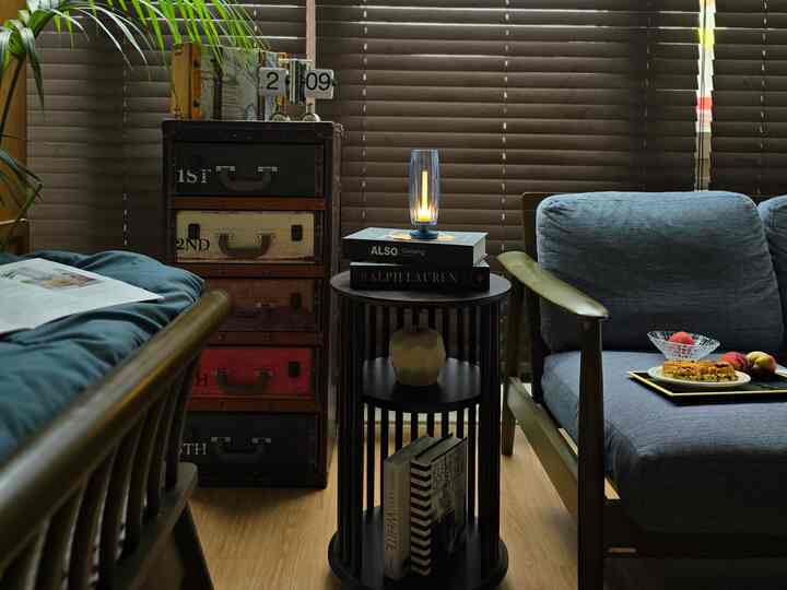 Wood tone and vintage style living room featuring blue sofas and a round side table with a lit table lamp, creating a cozy atmosphere