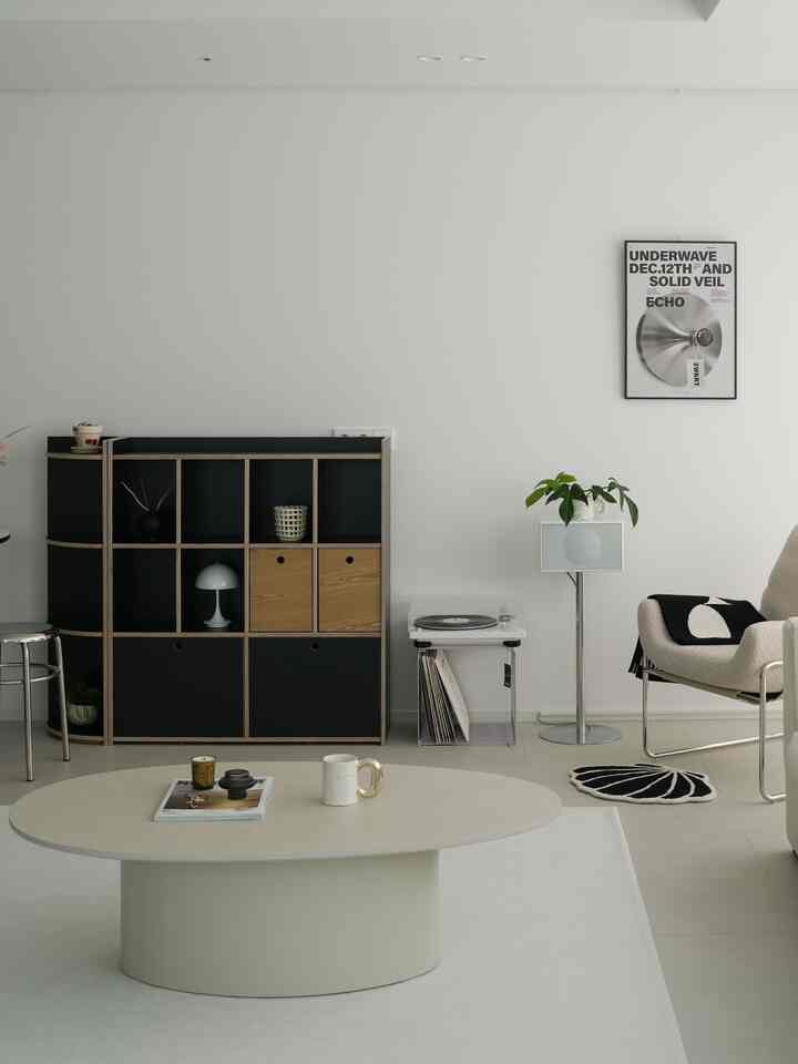 Bright white and black living room featuring a single sofa and a metallic-themed poster, creating a sophisticated atmosphere