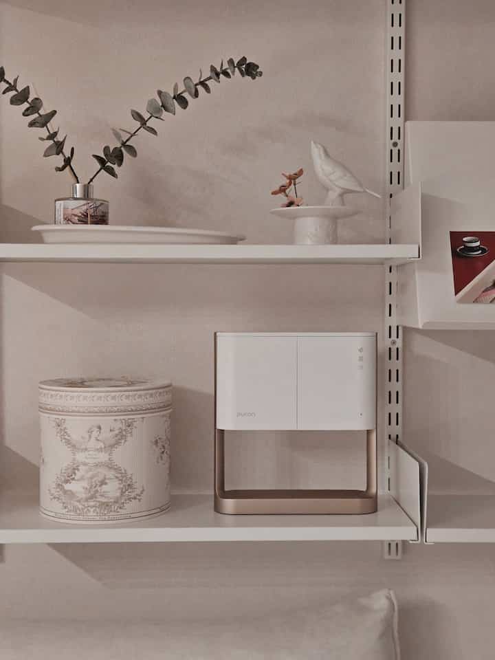 ホワイトトーンのバスルーム棚に歯ブラシ除菌器と装飾オブジェが配置された、清潔感のあるモダンなインテリア