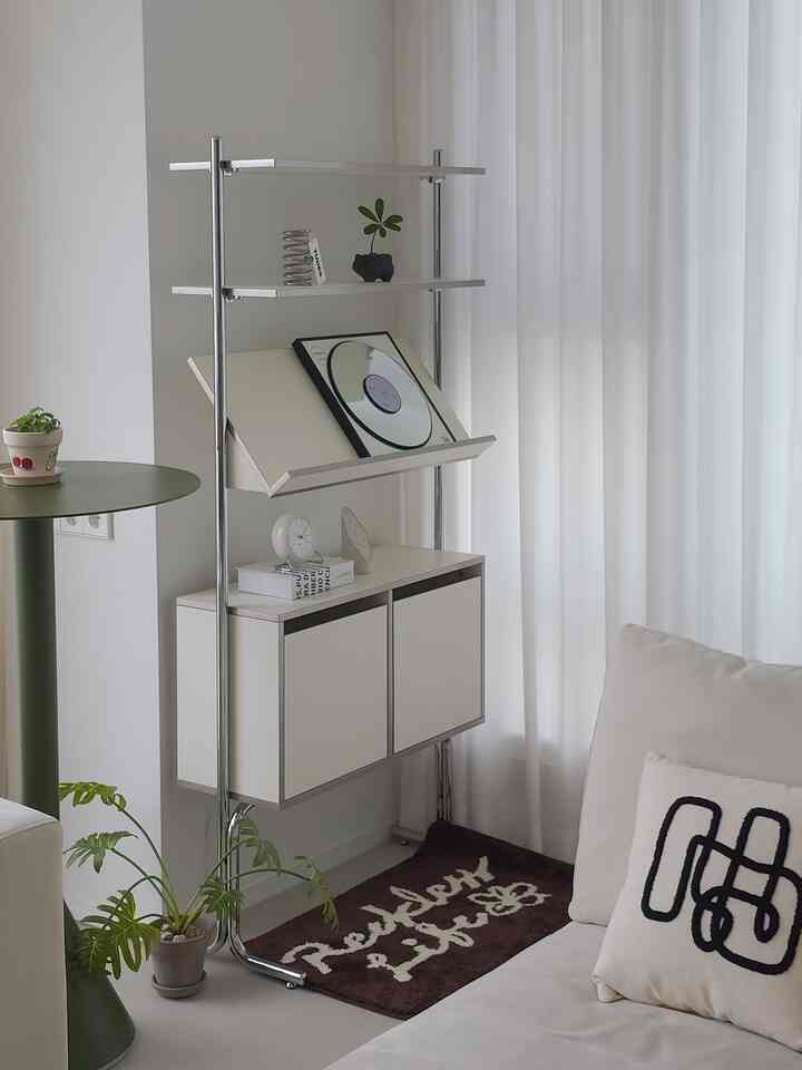 ホワイトトーンのリビング、モダンなキャビネットにミニ観葉植物や鏡、時計などが配置された雰囲気のあるインテリア