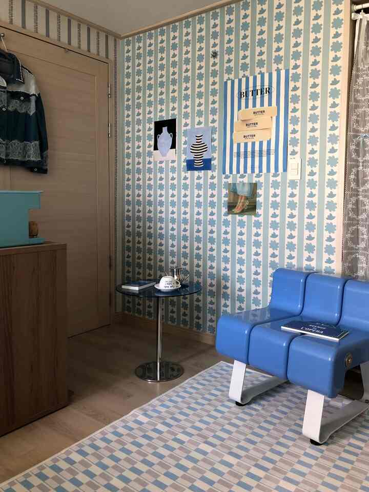 パステルブルーとナチュラルウッド調のリビング、パターン壁紙とモダンなブルーチェアが調和する印象的な空間