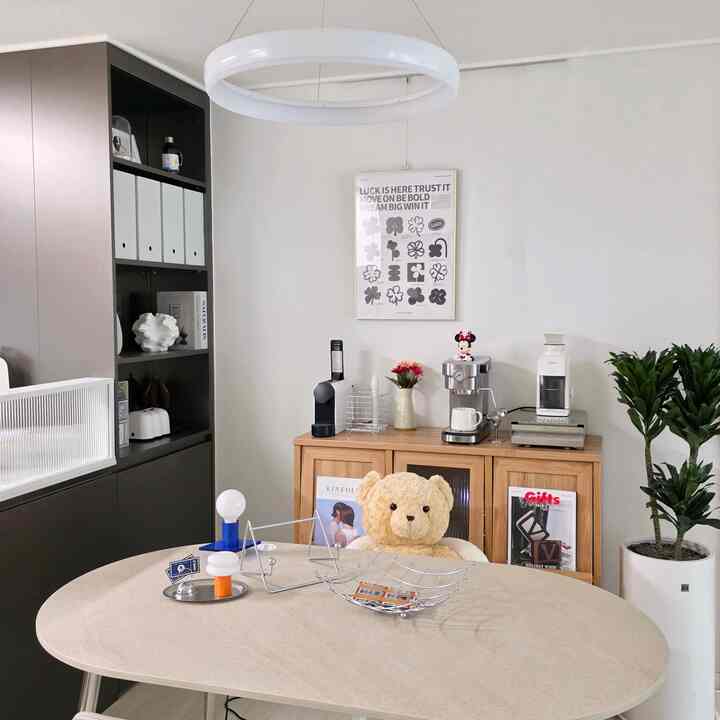 A minimal dining room in white and wood tones featuring coffee machines and plants, creating a cozy atmosphere