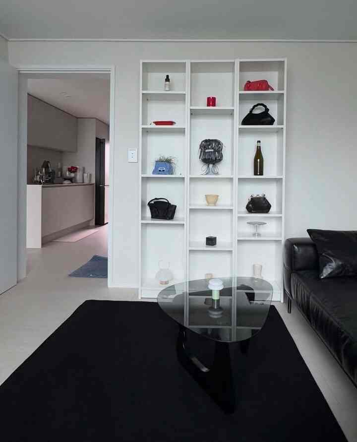Modern mid-century modern living room featuring white walls and furniture, black leather sofa, and black rug creating a clean atmosphere