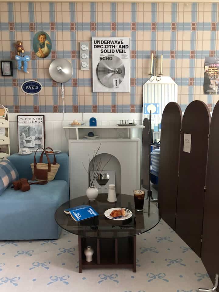 青と白のトーンのリビング、ソファとコーヒーテーブル、アーチ型パーティションが配置された落ち着いたミッドセンチュリーモダンインテリア