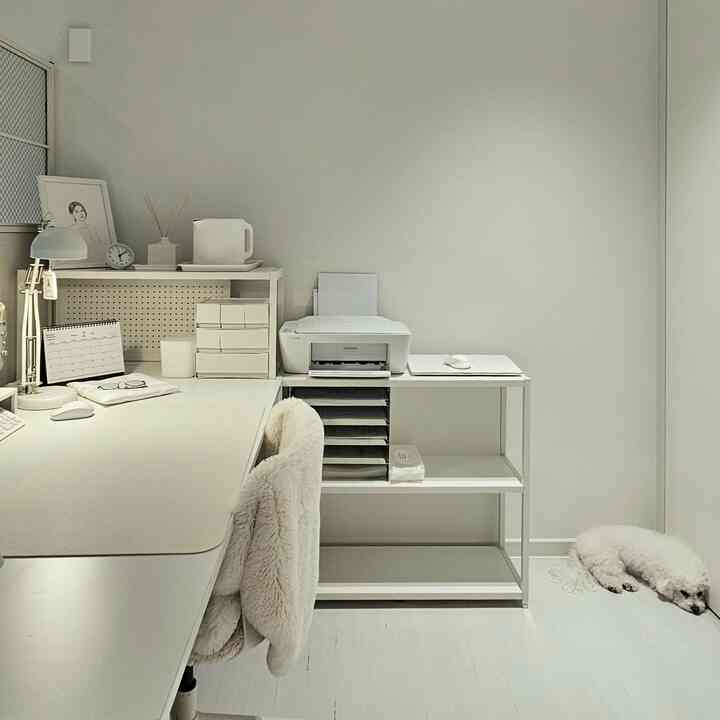 白を基調としたホームオフィス、広いデスクとオフィスチェア、プリンターが配されたシンプルで清潔感のあるインテリア