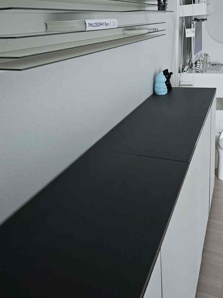 白と黒のモダンな書斎、スッキリとした収納キャビネットと本棚が配置された落ち着いた雰囲気のインテリア