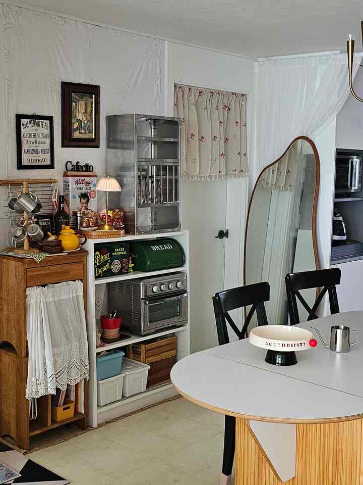 Small kitchen dining area with white and wood tones, cozy with vintage decor and functional storage units