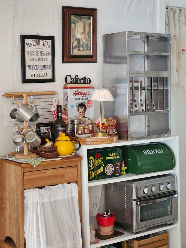 White and brown wood tone vintage kitchen space featuring storage cabinets and decorative items with cozy atmosphere